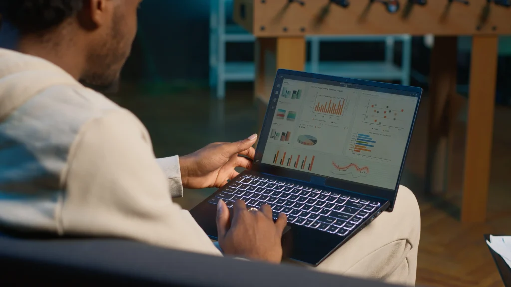 Profissional analisando gráficos e indicadores de desempenho no notebook para gestão de tráfego pago.
